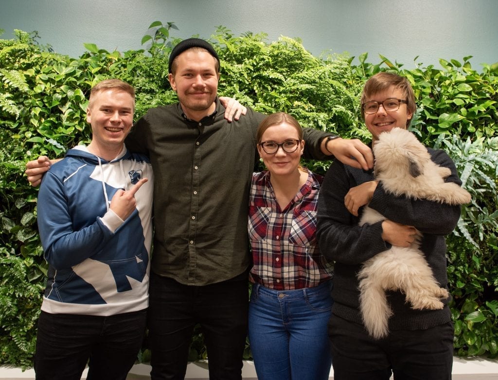 Evermade analytics and marketing team (Juha, Markus, Vilma, Mikael and his dog Rapsu) standing in front of the plant wall at the Evermade office