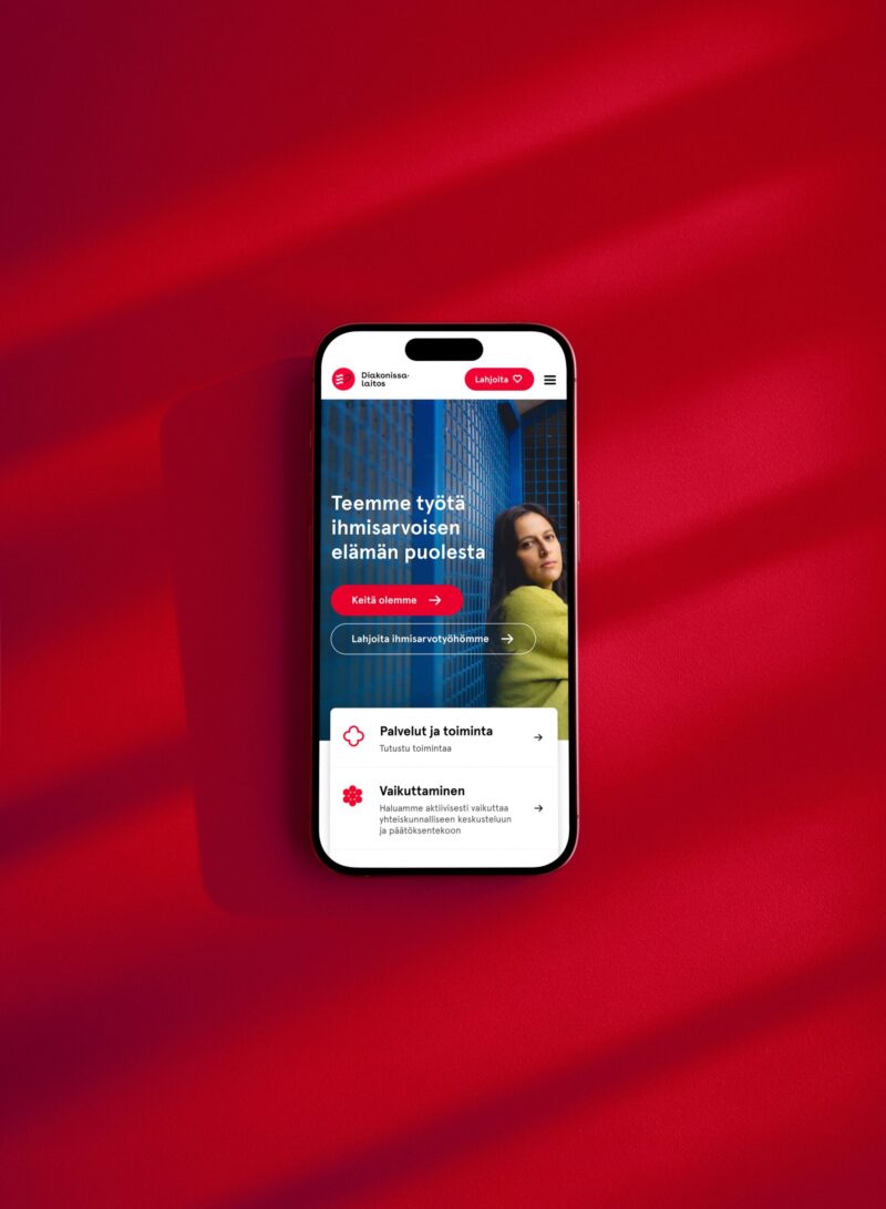 Punaisella taustalla keskellä älypuhelin, jonka näytöllä Diakonissalaitoksen mobiiliverkkosivu: otsikko "Teemme työtä ihmisarvoisen elämän puolesta", naisprofiilikuva sekä palvelu- ja valikkokortteja.