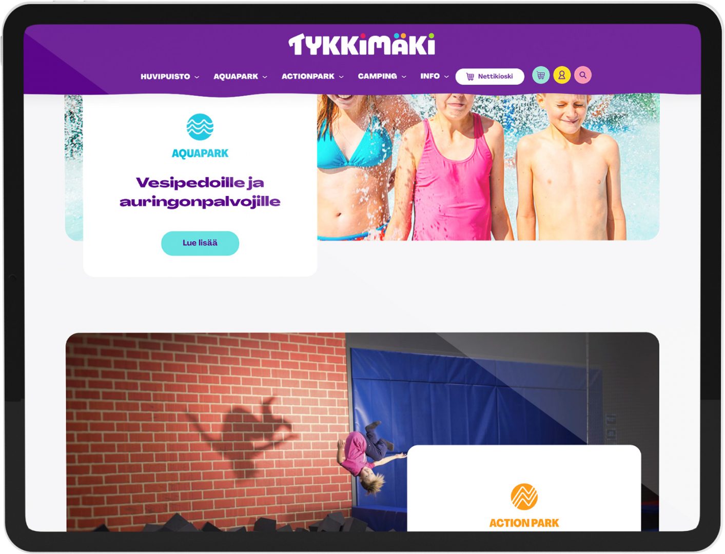 Tablet displaying the Tykkimäki website with a purple header and logo, a top aquapark banner featuring three children in swimsuits, and a lower action-park photo of a person mid-jump casting a shadow on a brick wall.