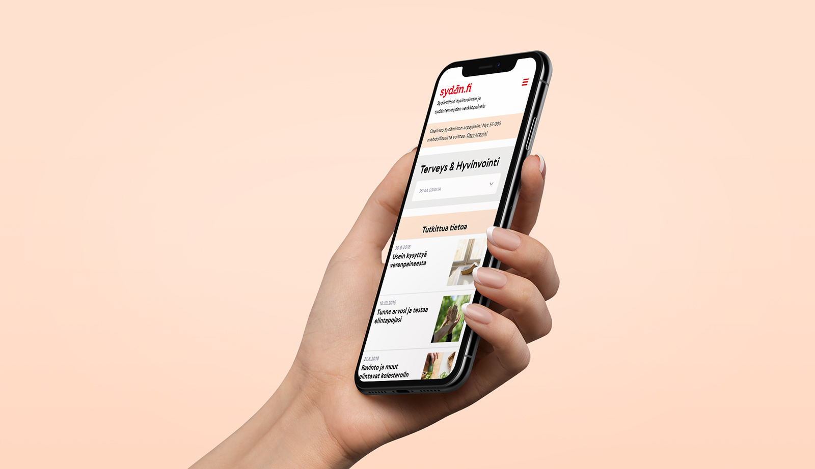 Käsi pitelee älypuhelinta, näytöllä Suomen Sydänliiton mobiiliverkkosivu, jossa näkyy sisältökortteja ja valikko vaalean persikkaisella taustalla.