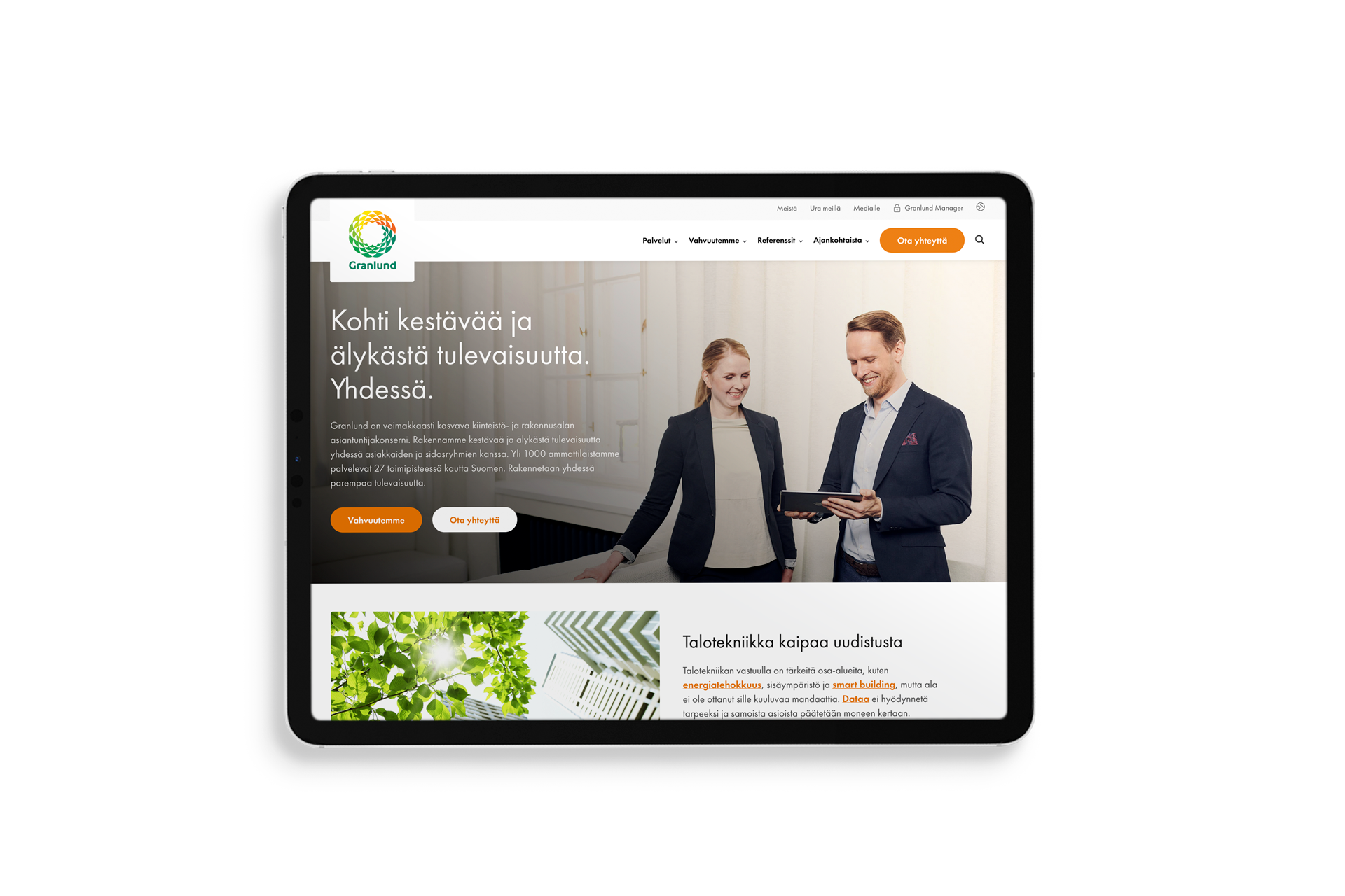 Tablettimockup mustalla taustalla, jossa näkyy Granlundin etusivu: yläkulmassa vihreä logo ja valikko, suuri hero-kuva kahdesta liiketoimintapukeiseen pukeutuneesta henkilöstä katsomassa tablettia, vasemmalla otsikko "Kohti kestävää ja älykästä tulevaisuutta. Yhdessä." ja oranssit toimintapainikkeet sekä alemmin vihreä kasvi- ja tekstikortti.