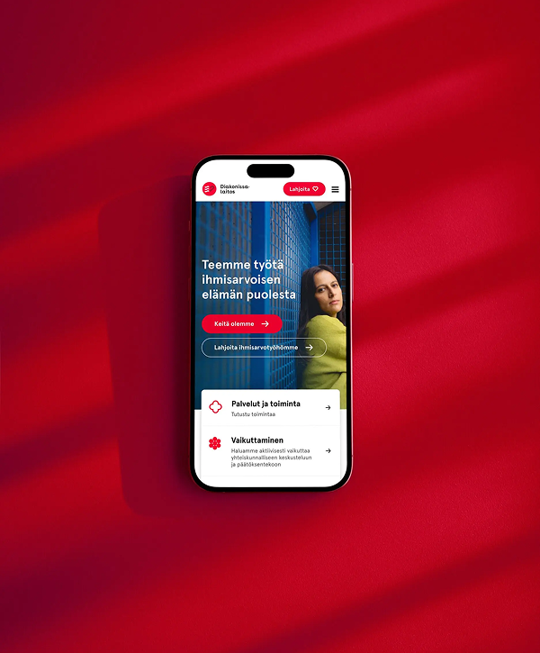 Smartphone mockup centered on a textured red background with diagonal shadows, showing the Diakonissalaitos mobile homepage in Finnish featuring a blue building image, a woman in a green sweater, a headline about human dignity, and visible call-to-action buttons including a "Lahjoita" (donate) button.