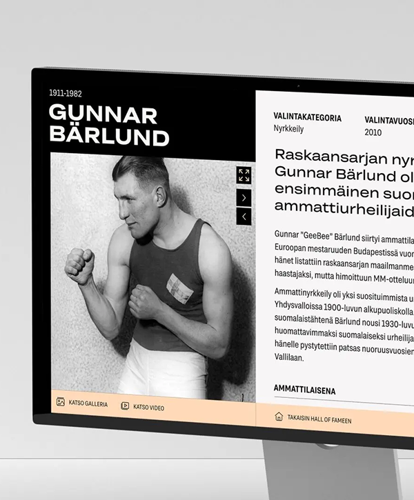 Screenshot of the Finnish Film Foundation’s Digital Hall of Fame displayed on a desktop monitor: left column shows a black-and-white portrait of a vintage male boxer in a singlet with a large bold name header above and gallery/video icons; right column shows Finnish-language biography text and navigation controls.