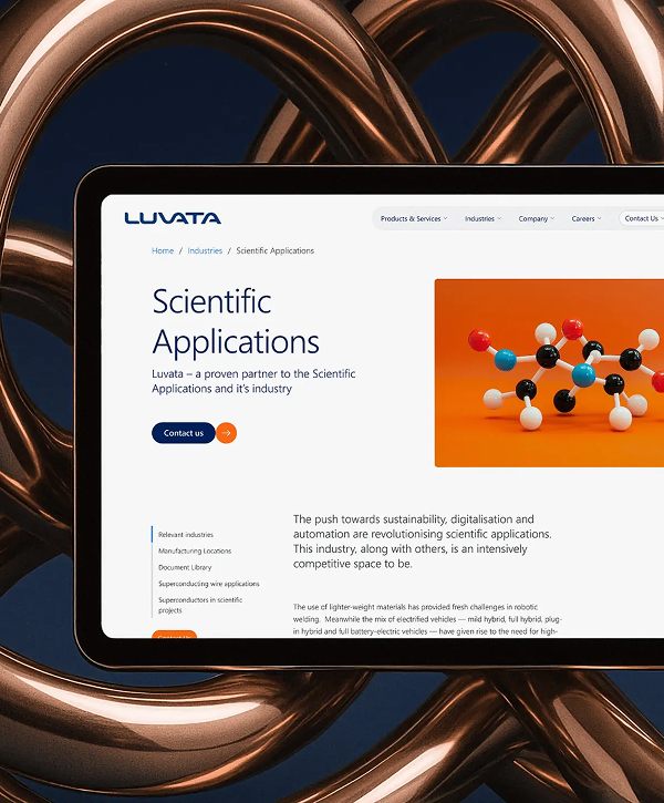 Close-up of a tablet showing Luvata’s "Scientific Applications" webpage — Luvata logo, headline "Scientific Applications" and a colorful molecular model on an orange panel — the tablet is framed by glossy coiled copper tubing against a dark background.