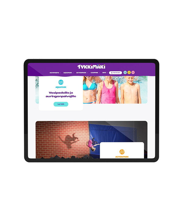 Tablet displaying the Tykkimäki website: purple header with logo, a top banner of three children in swimsuits at a water park, and a lower content area showing a person mid-jump casting a shadow on a brick wall with an "Action Park" card partially visible.
