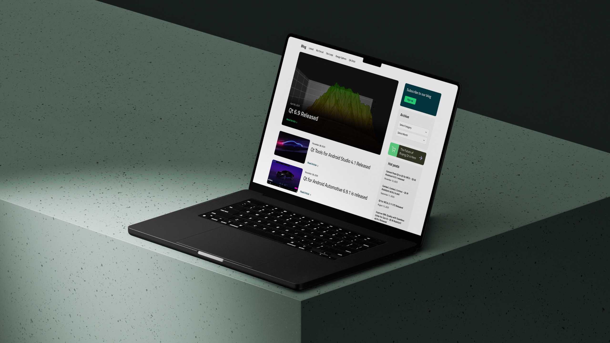 Dark laptop angled on a green speckled pedestal, screen displaying a website mockup with a colorful line graph, article thumbnails and a sidebar.